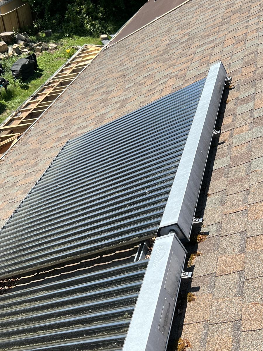 Two collector arrays on a shingle roof with a strip of open roof framing along the left edge