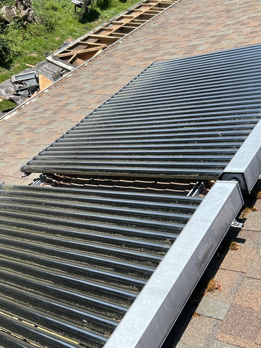 Collector tubes and manifold boxes on the roof beside torn out roofing and exposed framing