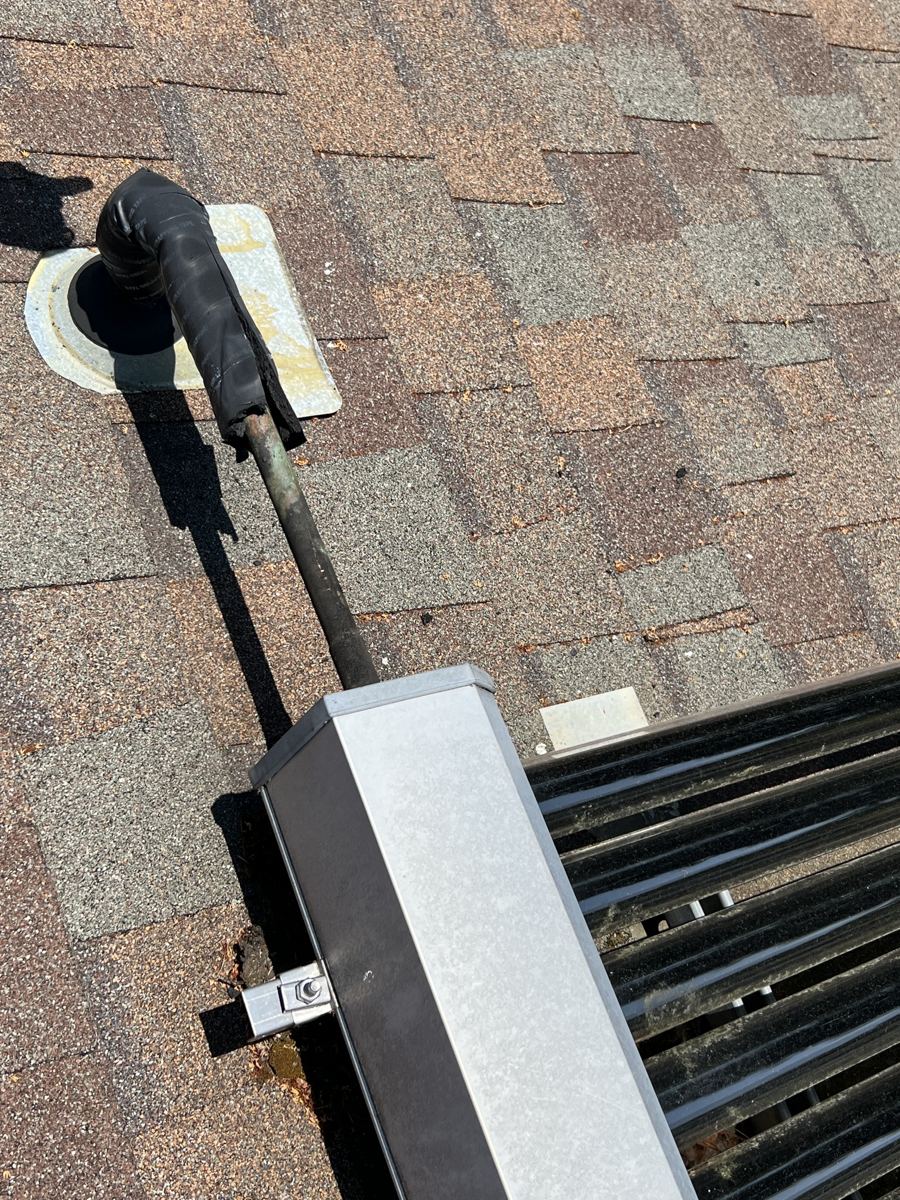 Copper pipe running from the end of a collector manifold box to an insulated, flashed roof penetration
